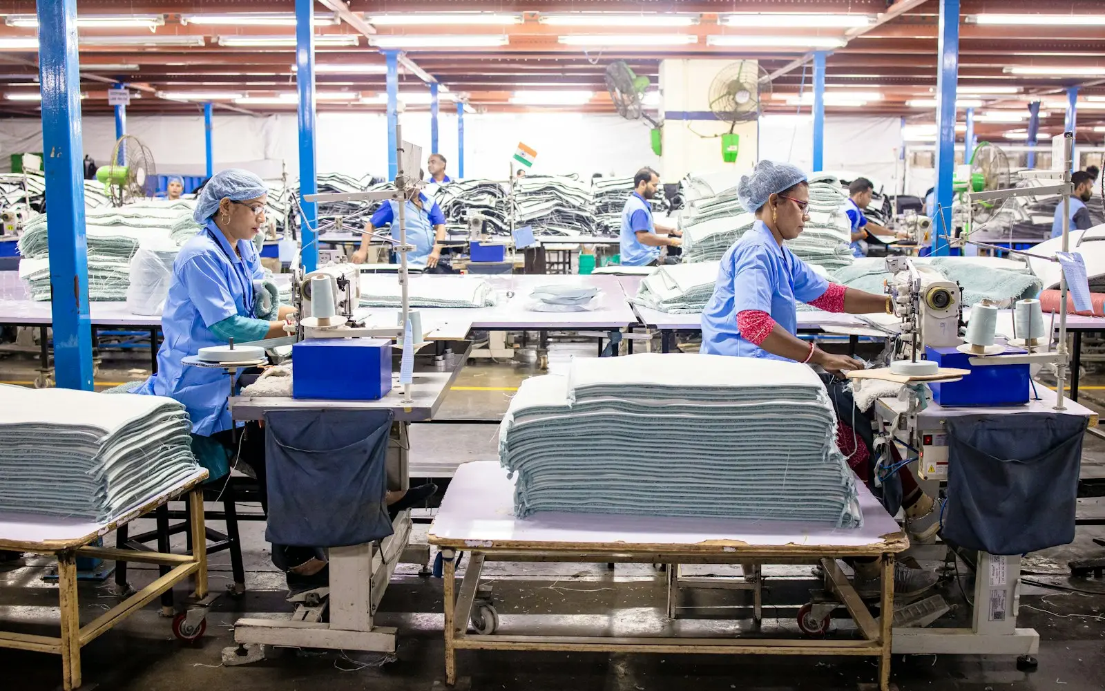 Factory workers at sewing stations in a large production hall
