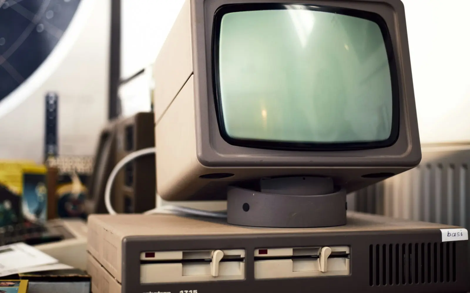 Vintage CRT computer monitor on top of disk drives in a workshop
