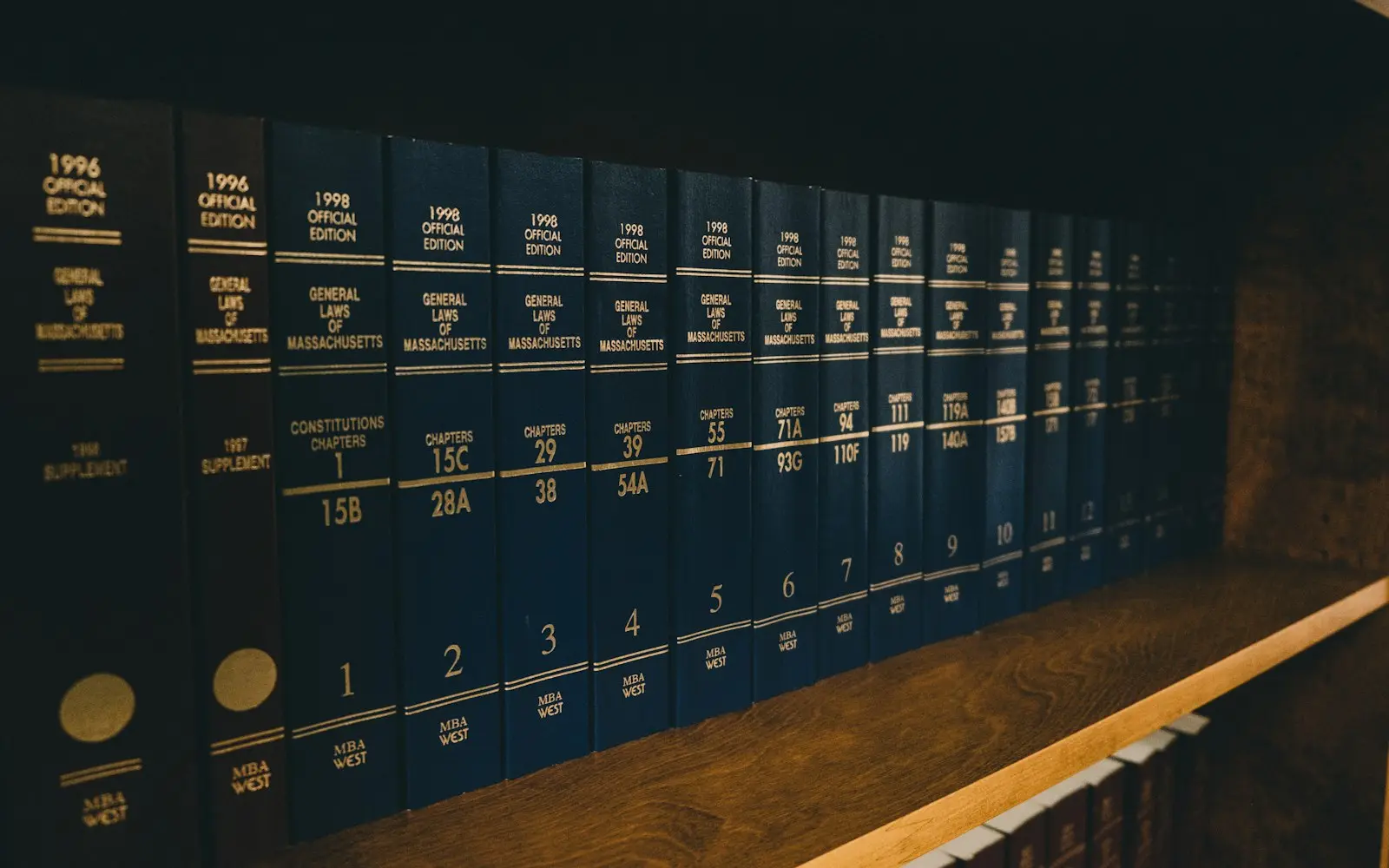 Row of blue bound law reports on a wooden shelf