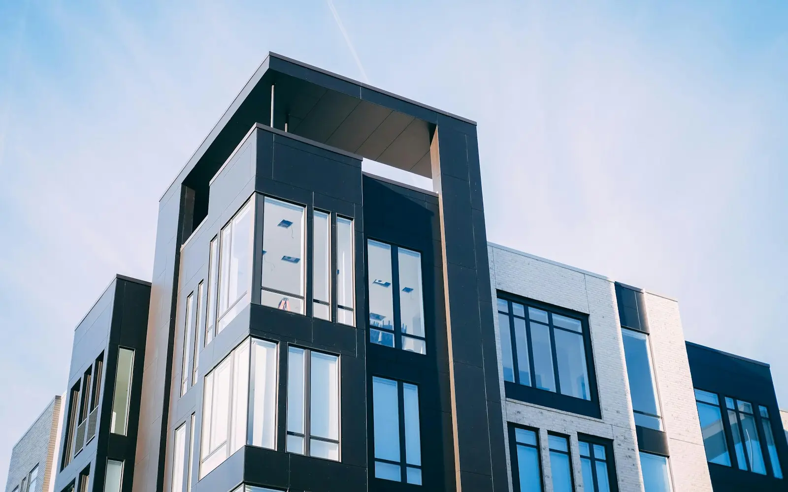 Modern apartment building with glass balconies against a pale blue sky
